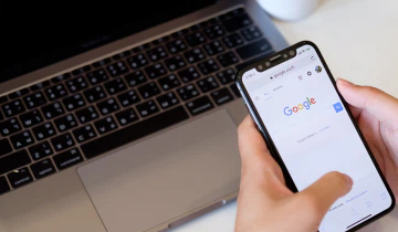 A shot of a mobile being held by two hands, with Google open.